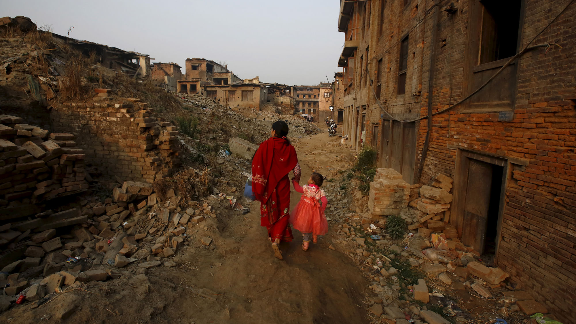 भूकंप से क्षतिग्रस्त इलाके से अपनी लड़की के साथ गुजरती एक नेपाली महिला (फोटो: रॉयटर्स)