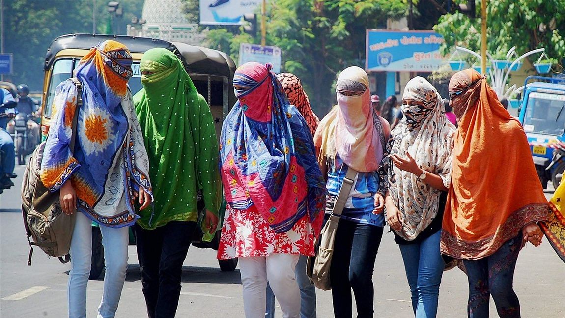 सूरत में मुंह पर कपड़ा बांध कर घर से बाहर निकली हैं ये लड़कियां (फोटो: PTI)