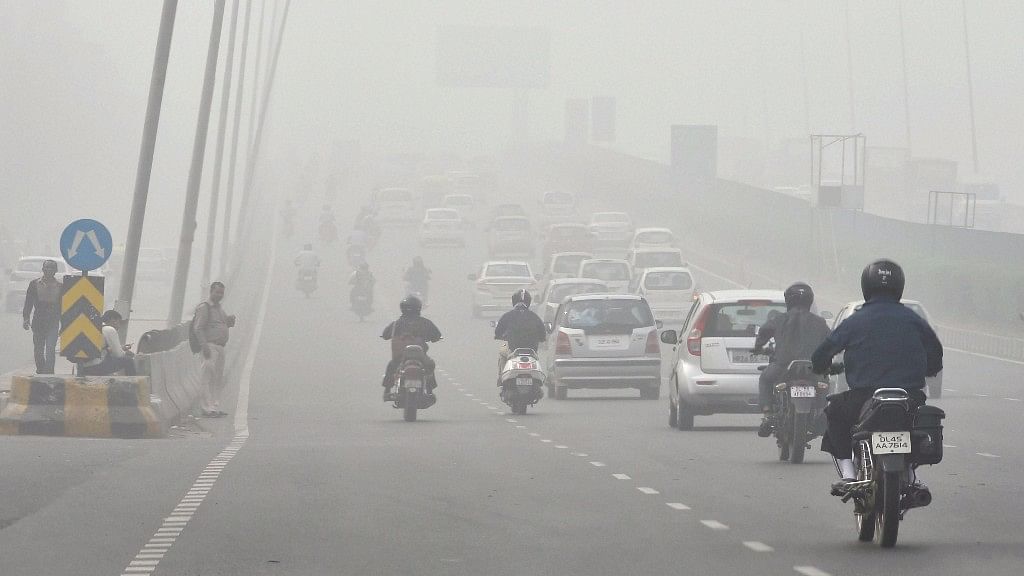 दिल्ली में छाई धुंध के बीच गुजरते वाहन
