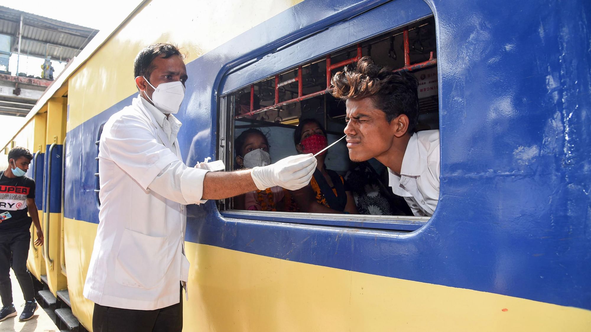 पटना में ट्रेन के अंदक बैठे शख्स का सैंपल लेता एक स्वास्थ्य कर्मचारी