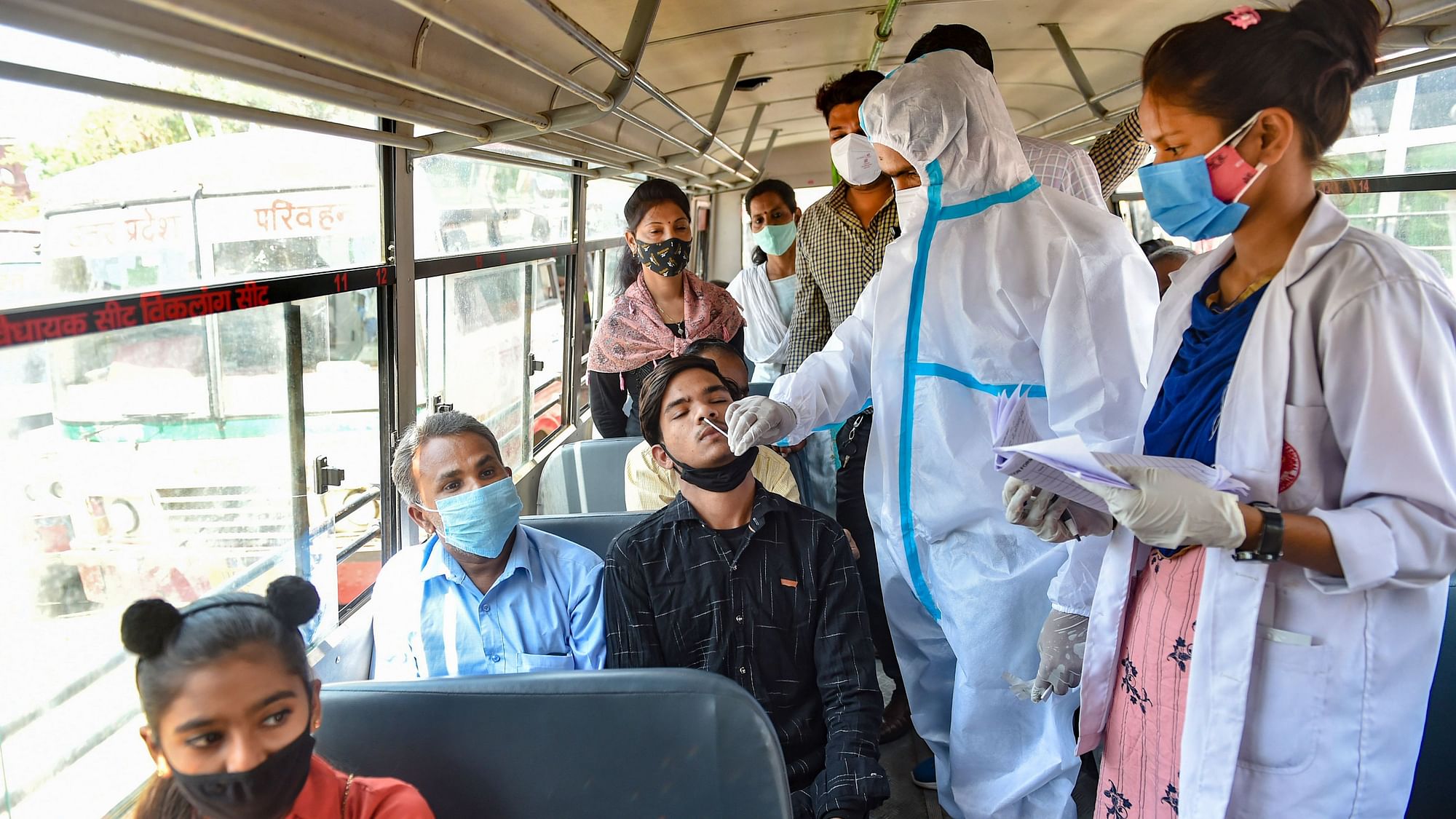लखनऊ में आलमबाग बस स्टेशन पर लोगों का टेस्ट करते मेडिकल कर्मचारी, 24 मई 2021 की तस्वीर