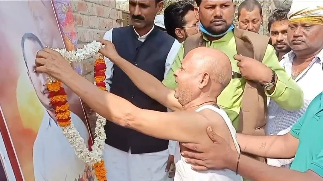 <div class="paragraphs"><p>बेटे की तस्वीर पर माला चढ़ाते पिता तिलकधारी यादव</p></div>