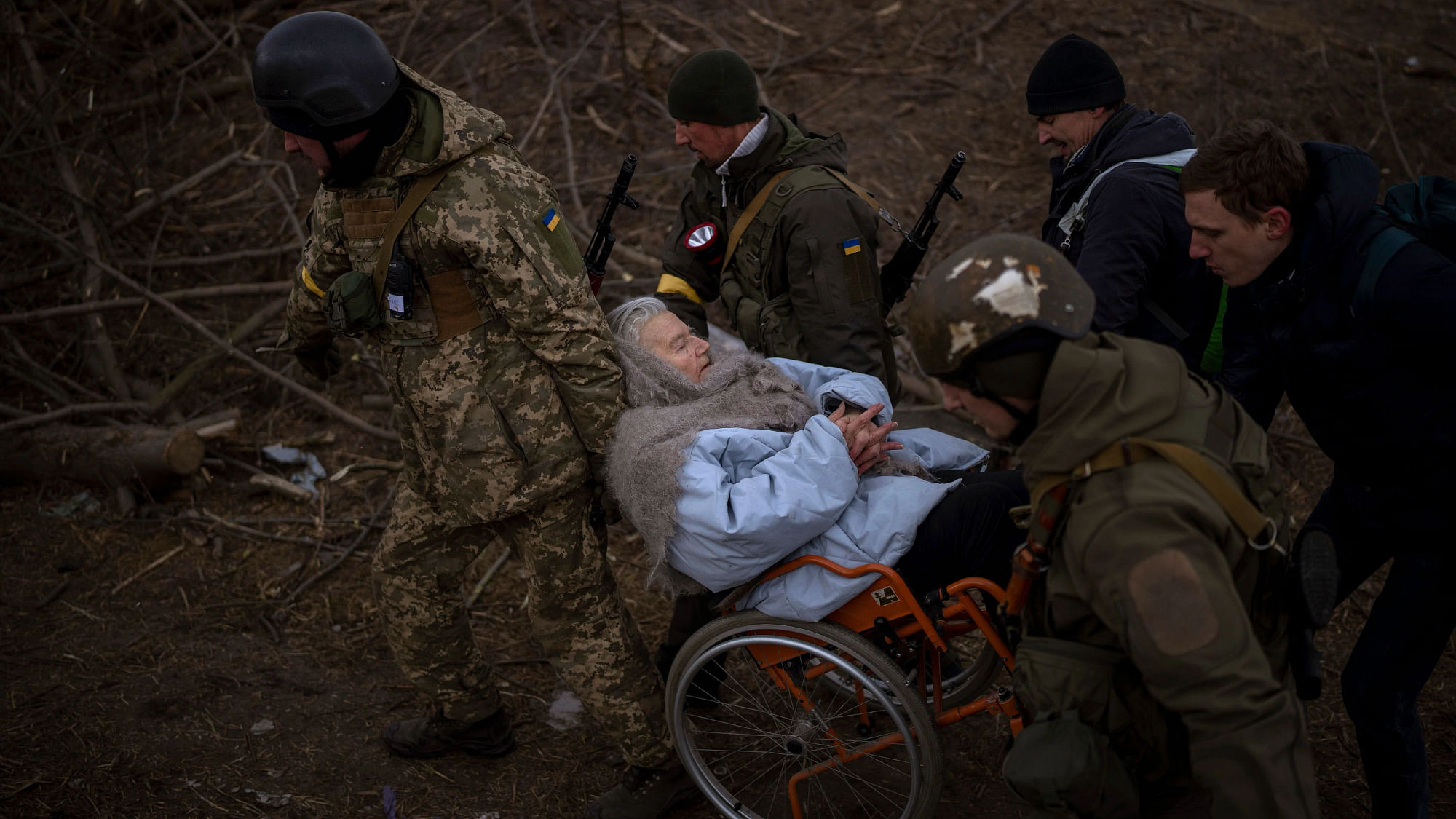<div class="paragraphs"><p>यूक्रेनी सैनिक और मिलिशियामेन एक महिला को व्हीलचेयर में ले जाते हुए (7 मार्च 2022)</p></div>