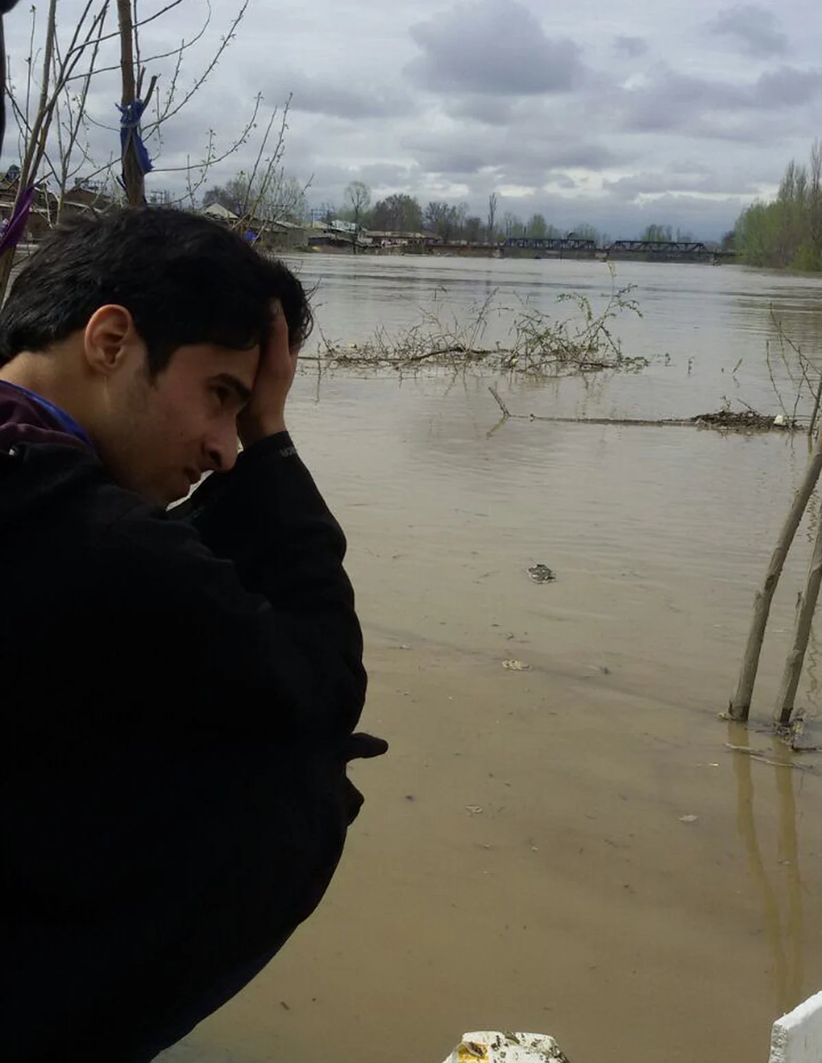 A Kashmiri youth examines the destruction sitting on the banks of river Jhelum in Pampore, 10 kms from Srinagar. (Photo: Mohammed Mukarram)