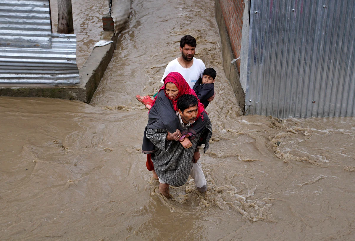 Men assist a woman and a child evacuate from a flooded area in Srinagar. (Photo: AP)