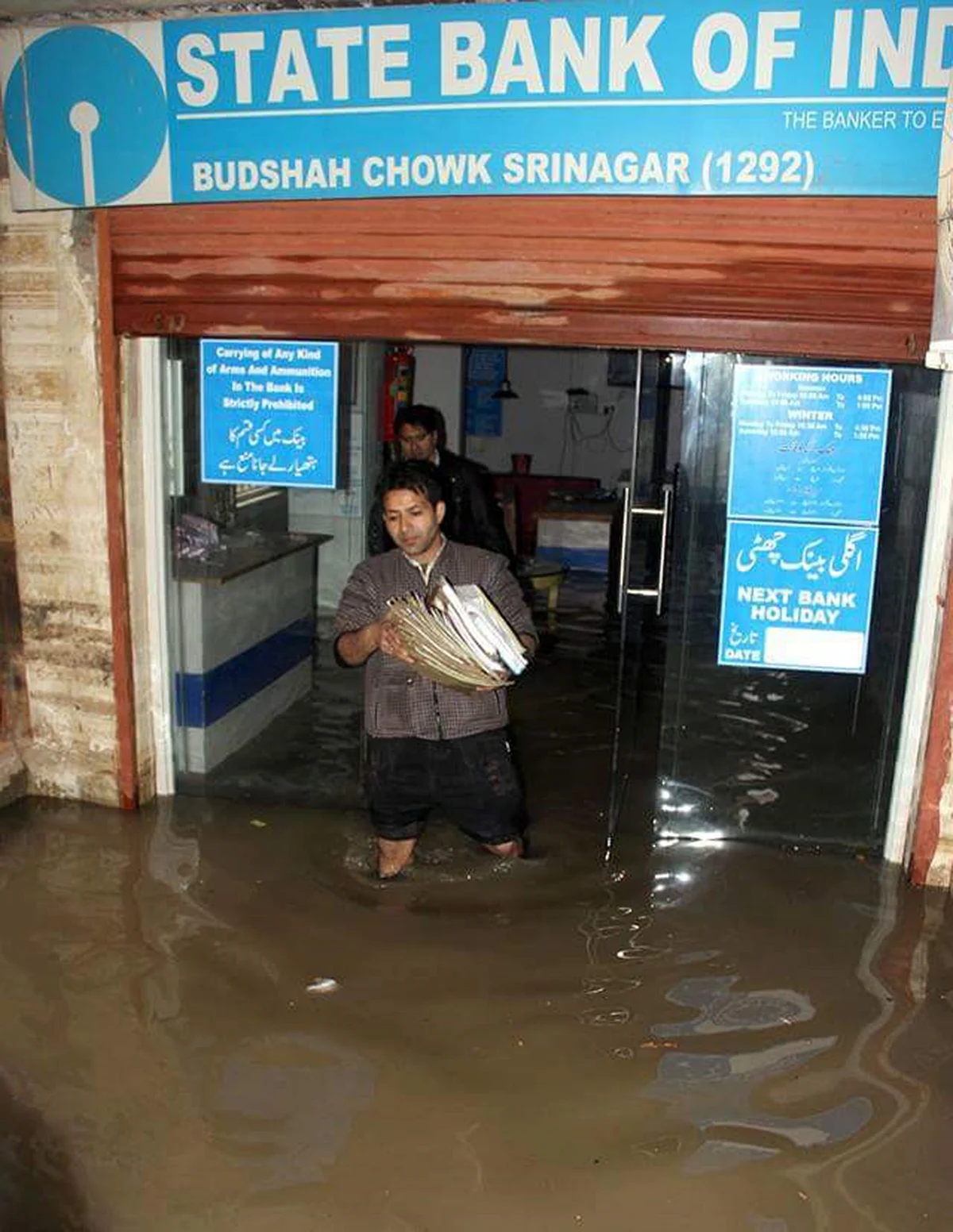 A bank employee carries files to safeguard them from flood waters in Srinagar. (Photo: Mushtaq Khan)