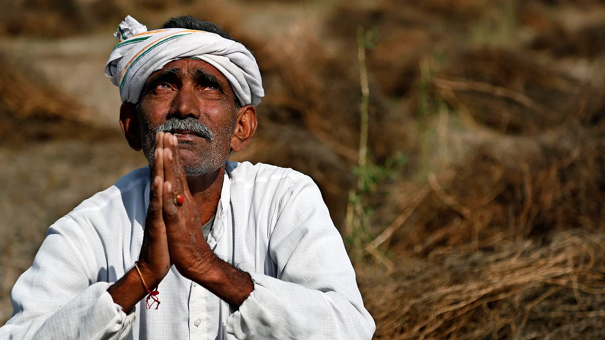An Indian farmer looks skyward as he sits in his field with wheat crop that was damaged in unseasonal rains and hailstorm at Darbeeji village, in Rajasthan. (Photo: AP)