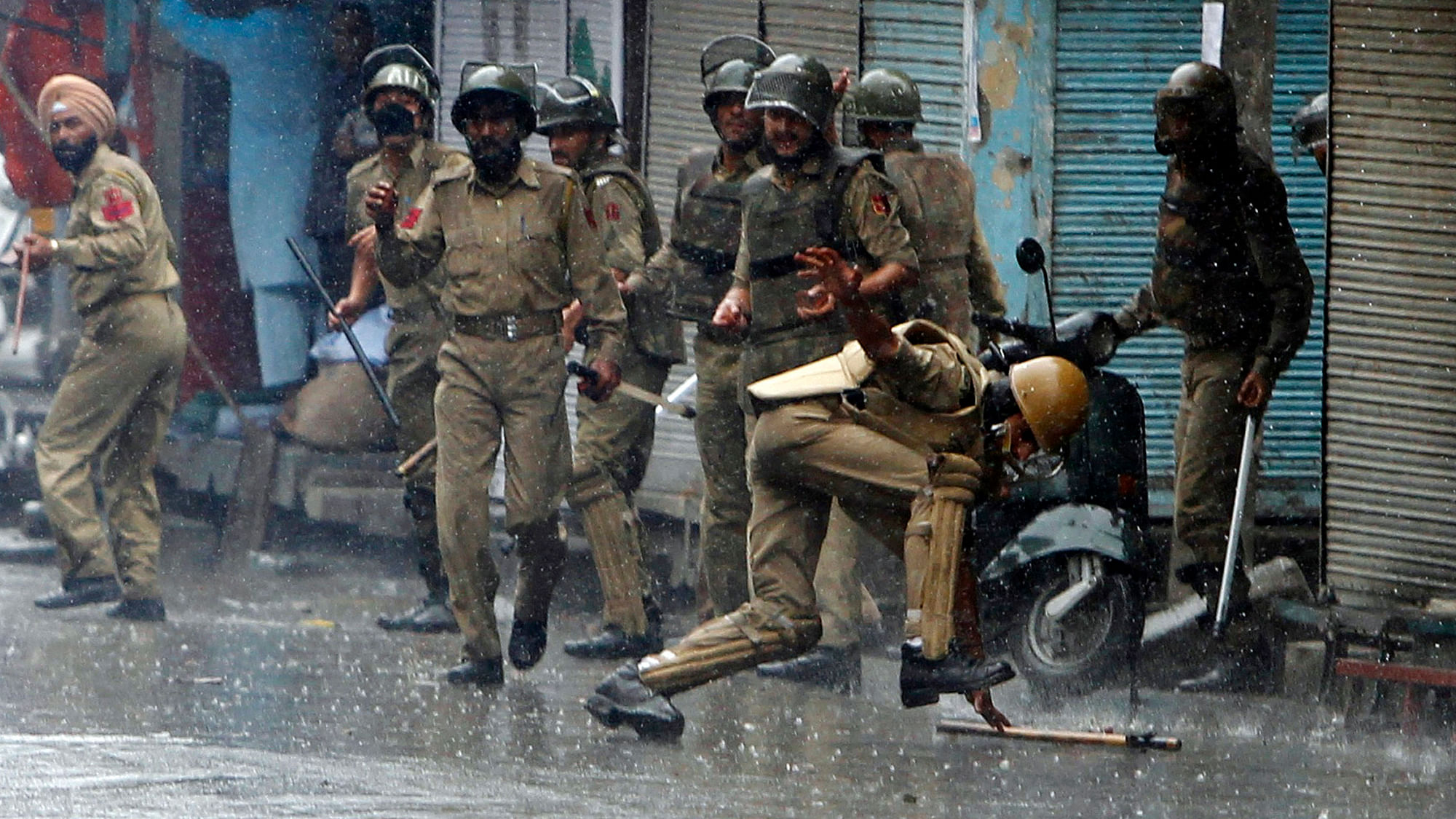 An Indian policeman falls after throwing a piece of stone towards protesters in Srinagar. (Photo: Reuters)&nbsp;