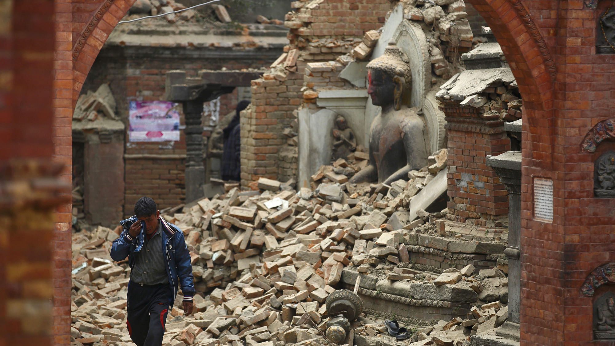 A man cries as he passes by a damaged statue of Lord Buddha in Bhaktapur, a day after the 2015 Nepal earthquake.