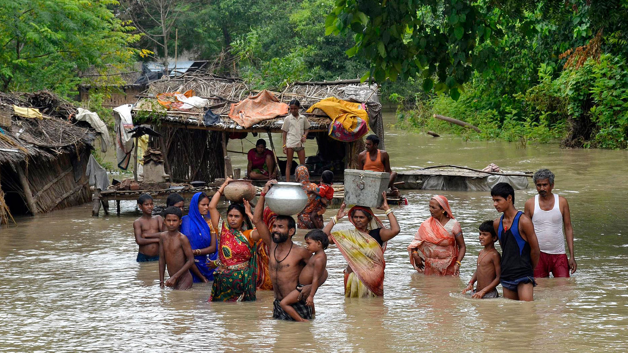 Flood-affected villagers carry their belongings  after heavy rains in Patna district, Bihar (Photo: Reuters)