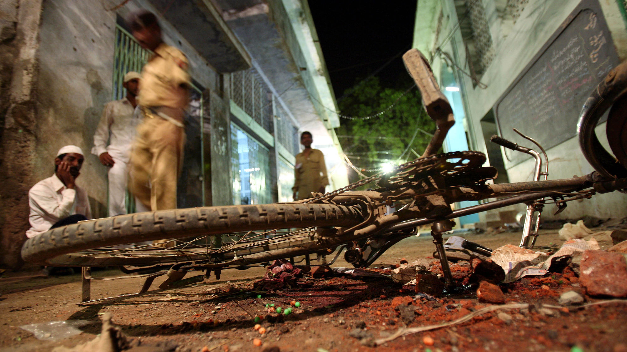People walk past a damaged bicycle lying at a blast site inside a mosque in Malegaon, 260 km northeast of Mumbai 9 September.(Photo: Reuters)