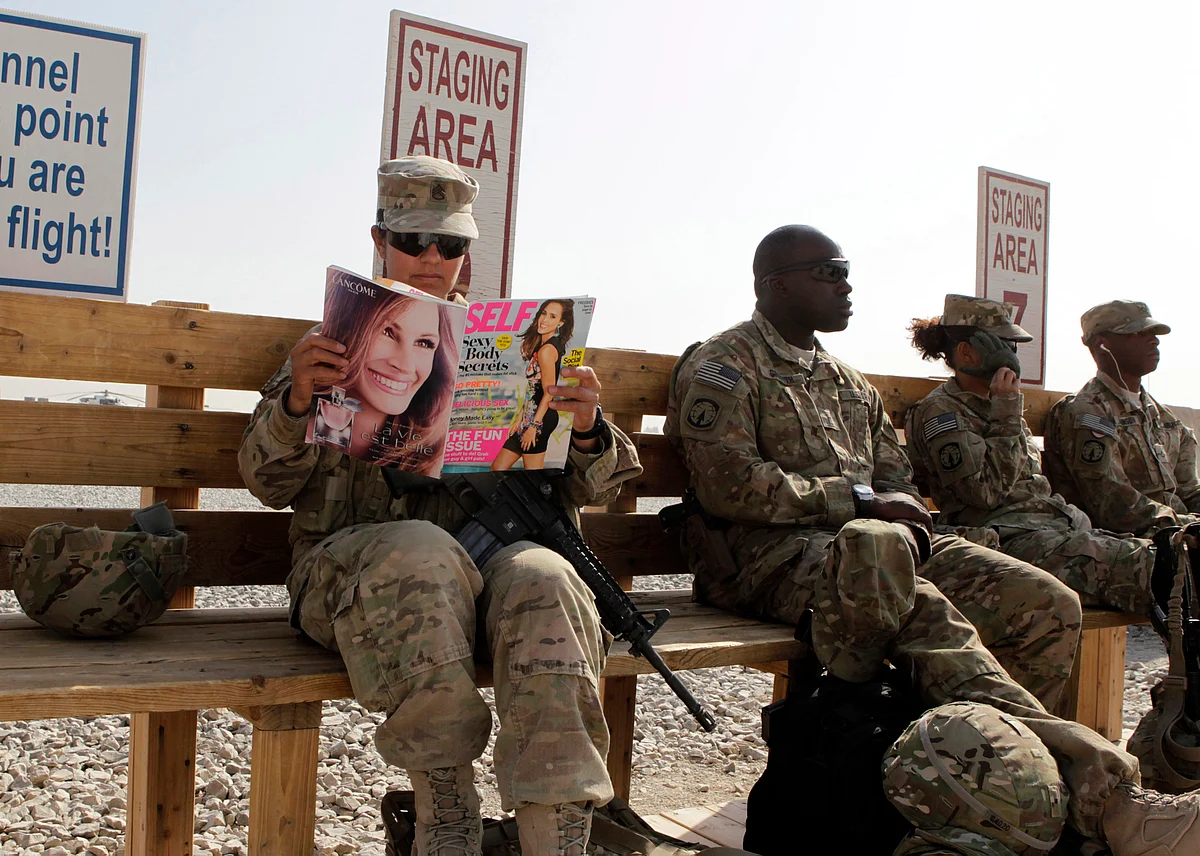 <!--StartFragment-->US Army soldier SSG Norma Gonzales of 426 Civil Affairs Battalion reads a magazine next to fellow soldiers while waiting to be ferried by a helicopter to different US military bases in Kandahar, southern Afghanistan. (Photo: Reuters)<!--EndFragment-->