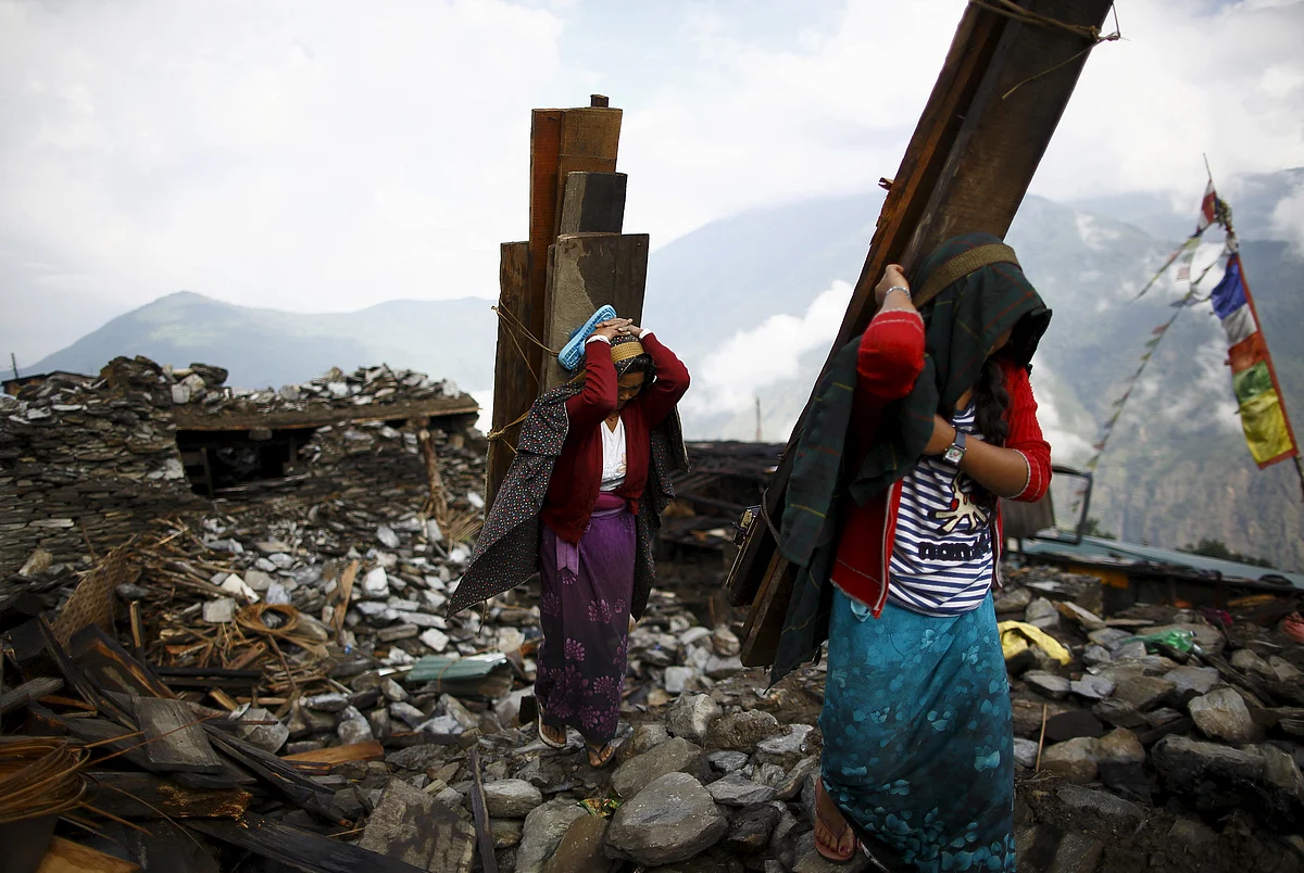 An earthquake victim, carrying a tin roof to rebuild a house, walks along the entrance gate of Barpak village at the epicenter of the April 25 earthquake in Gorkha district, Nepal. (Photo: Reuters)