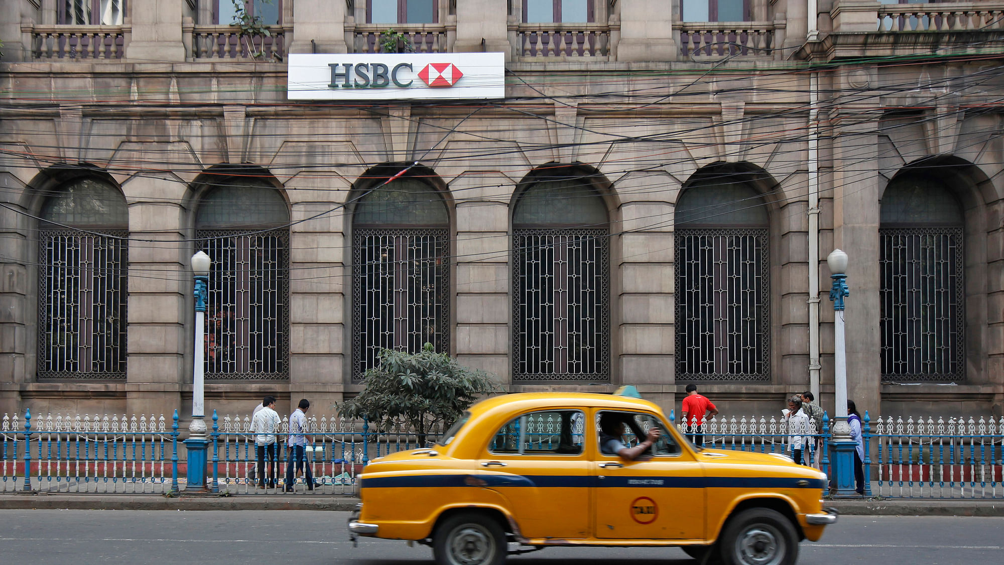 A yellow ambassador taxi drives past the HSBC bank building in Kolkata.&nbsp;
