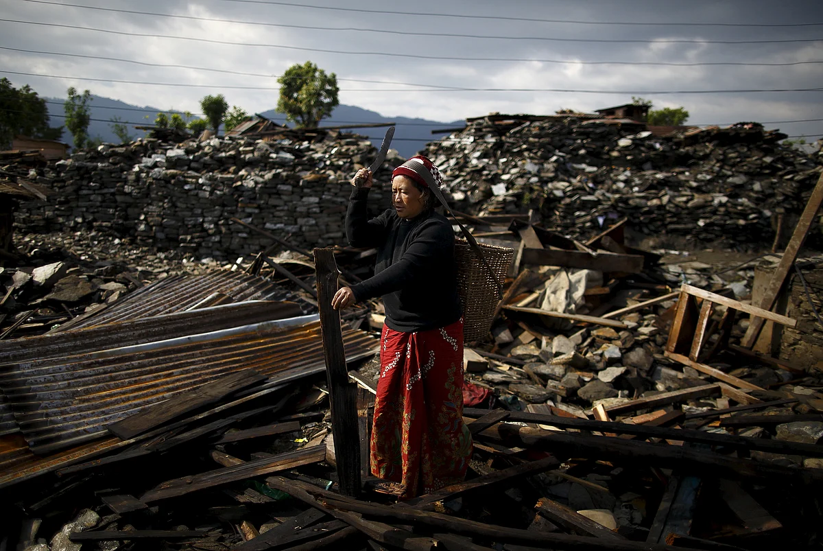 An earthquake victim cuts wood from the debris of her house in Barpak village at the epicenter of the April 25 earthquake in Gorkha district, Nepal. (Photo: Reuters)