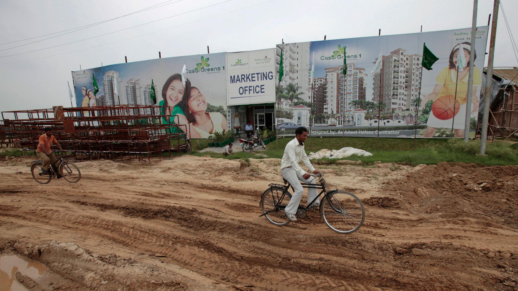 Men cycle past a closed booking centre for under-construction residential apartments at Greater Noida.&nbsp;