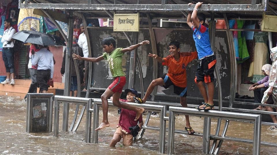 Children enjoying at a water logged road as it rains in Mumbai. (Photo: PTI/Shashank Parade)