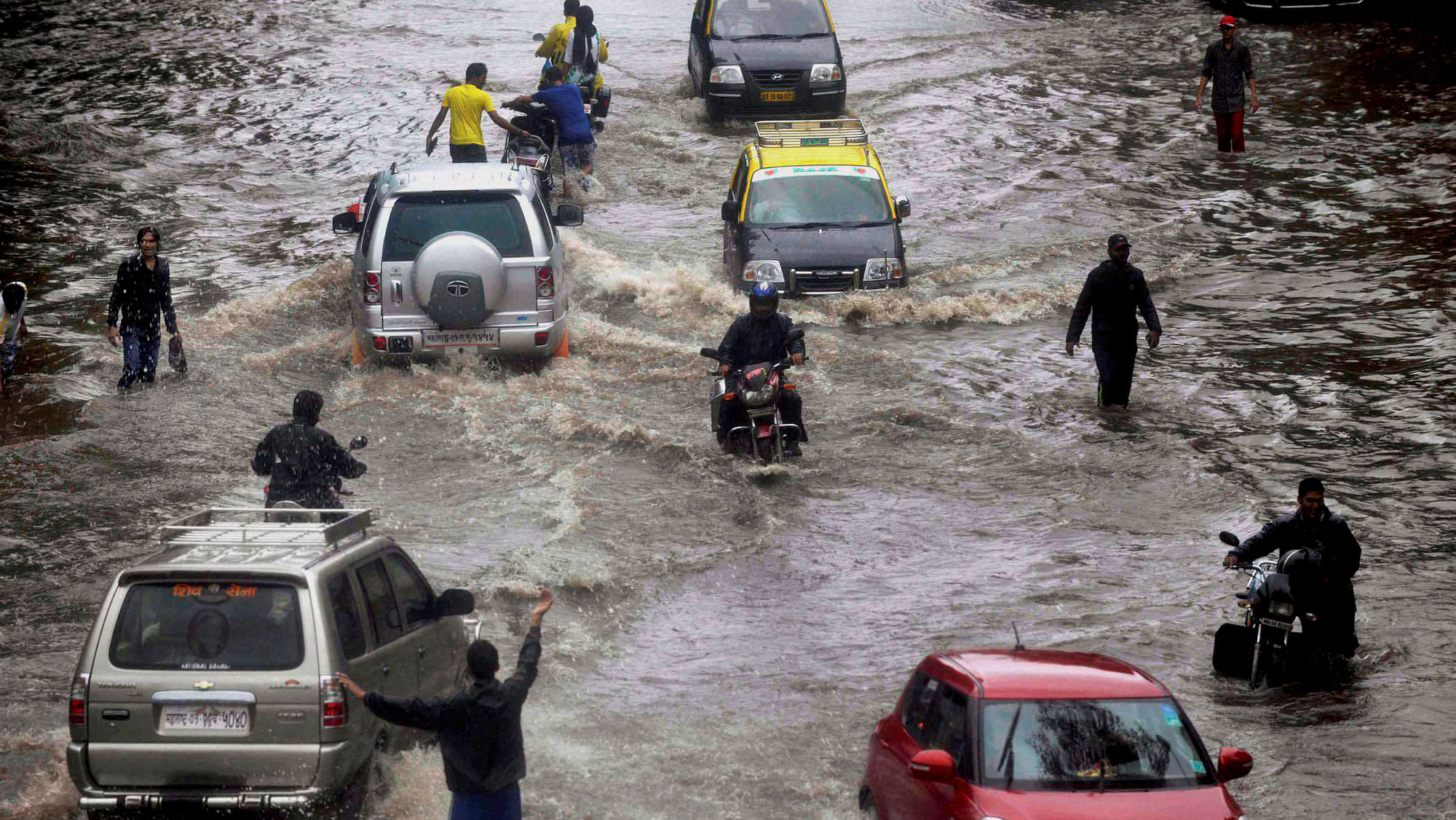 People wade through a water logged road after heavy rains near Dadar in Mumbai