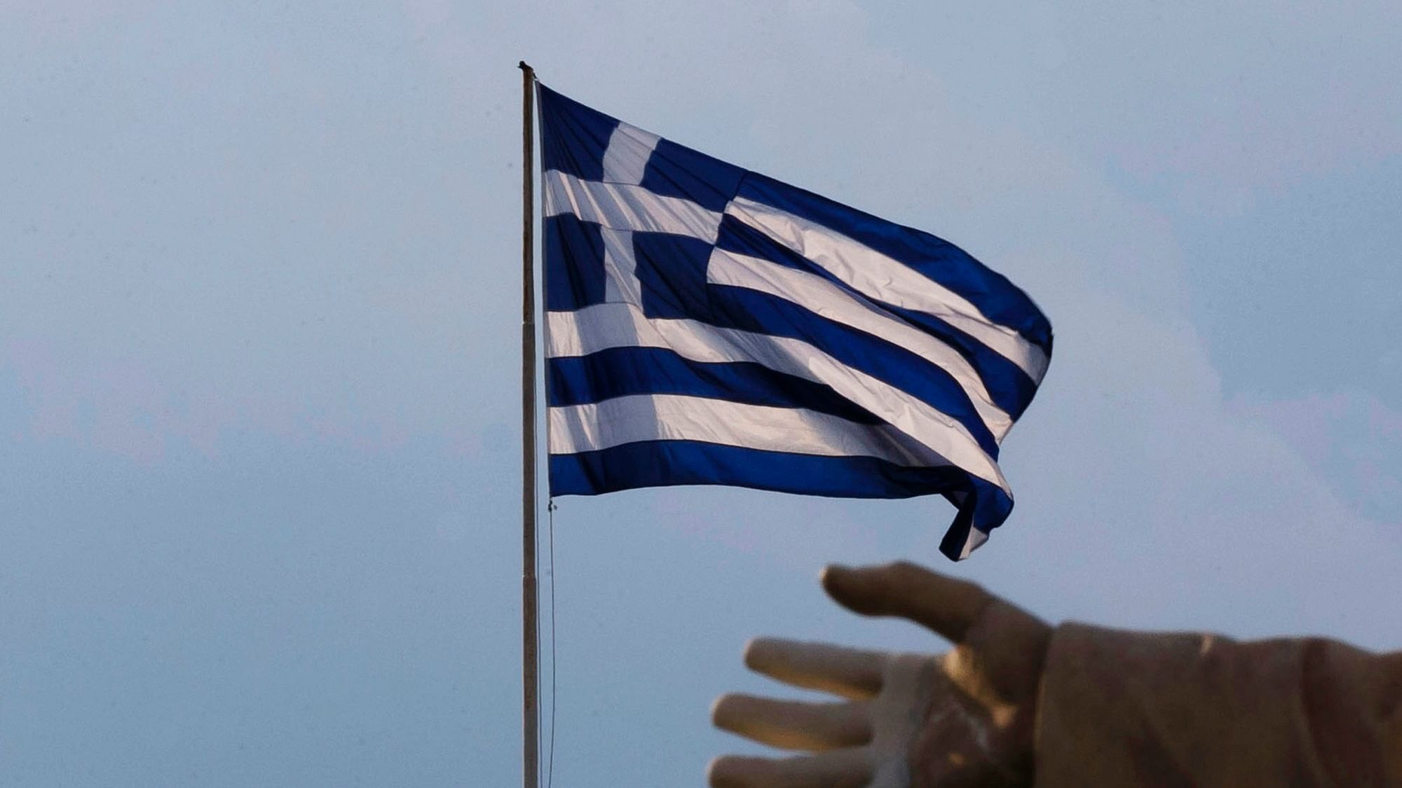  hand of a statue is seen as the Greek flag waves in Athens, Sunday, June 28, 2015. (Photo: AP)