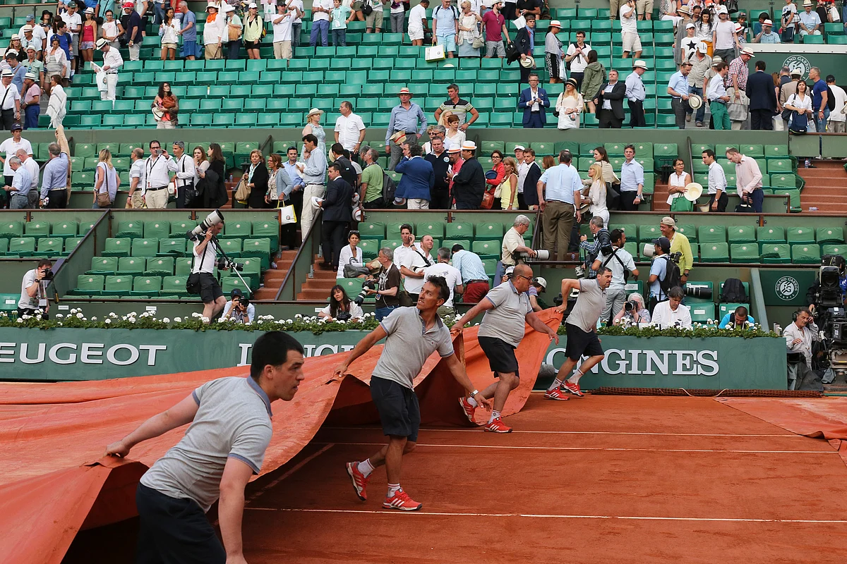 Spectators leave as stadium employees cover center court because of approaching rainstorms. (Photo: AP)
