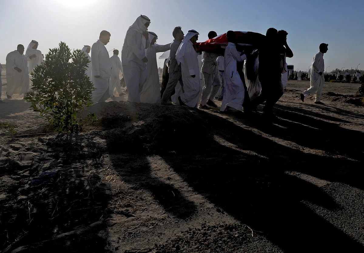 People carry the body of a victim in a mass funeral procession for 27 people killed in the suicide bombing at a Shia mosque in Kuwait. (Photo: AP)
