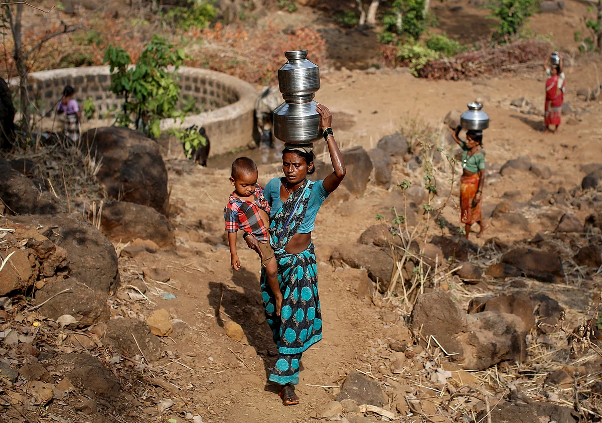 Shivarti, the second wife of Namdeo, holds her grandson while carrying metal pitchers filled with water from a well outside Denganmal village, Maharashtra, India, April 21, 2015. (Photo: Reuters)