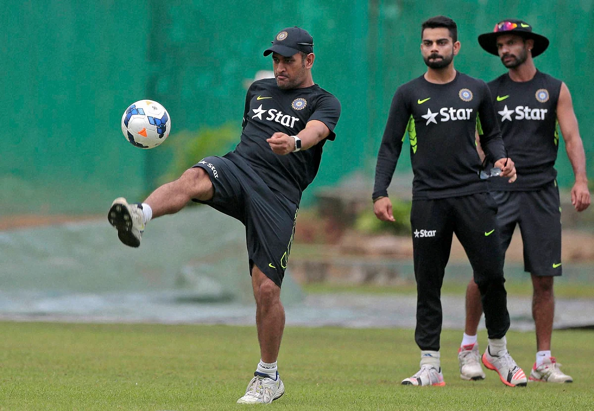 India’s captain Mahendra Singh Dhoni plays with a soccer ball, as his teammates Virat Kohli and Shikhar Dhawan watch during a practice session a day ahead of their ODI match against Bangladesh in Dhaka (Photo: PTI)
