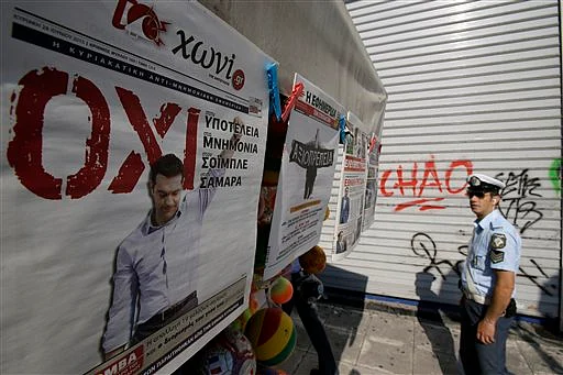Traffic police looks at the front page of newspapers after Sunday parliamentary decision in favor of the July 5 referendum. (Photo: AP)