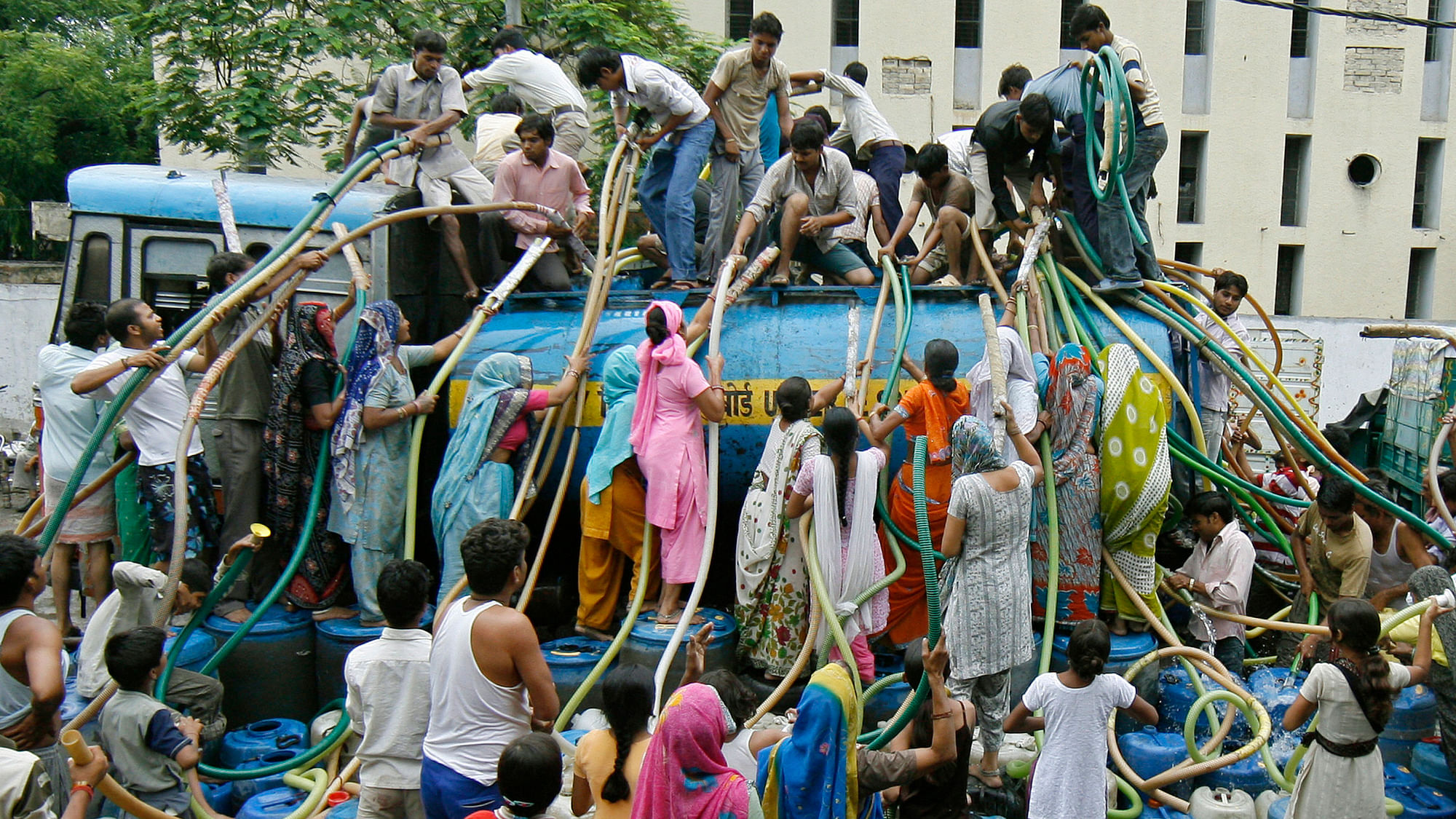Residents of a Delhi colony crowd around a water tanker provided by Delhi Jal (water) Board to fill their containers. (Photo: Reuters)<!--EndFragment-->