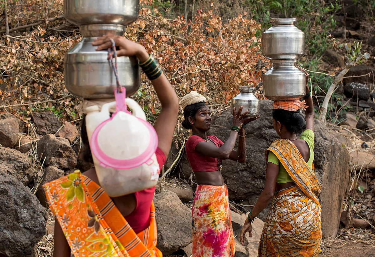 A woman helps another in carrying metal pitchers filled with water from a well outside Denganmal village, Maharashtra, India, April 20, 2015. (Photo: Reuters)
