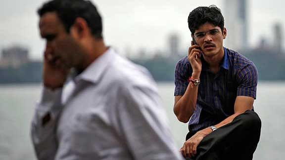 Men speak on their mobile phones on a seafront in Mumbai (Photo: Reuters)
