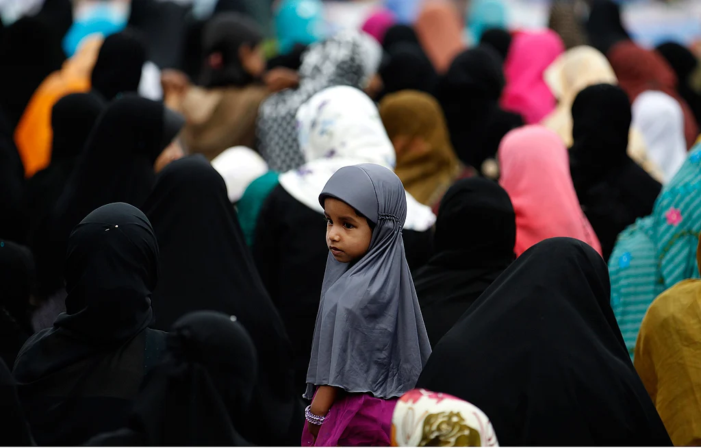 A girl looks on as Muslim women pray during morning prayers in Colombo, August 9, 2013. (Photo: Reuters)