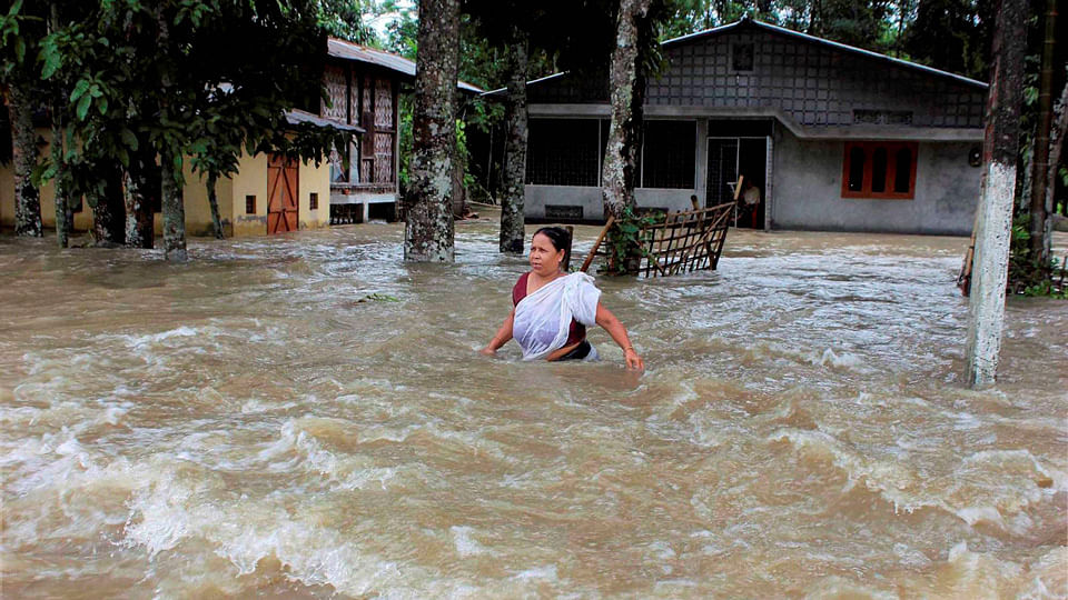 A woman walks through flood water at a village in Sonitpur district of Assam. (Photo: PTI)