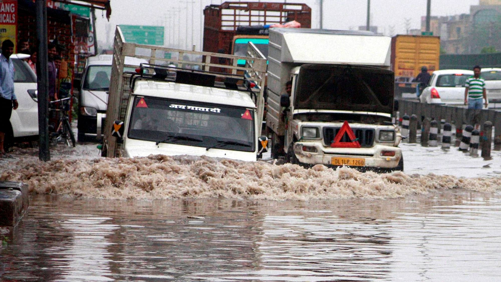 Vehicle moves through a water logged road after heavy rains in NCR region on Saturday. (Photo: PTI)