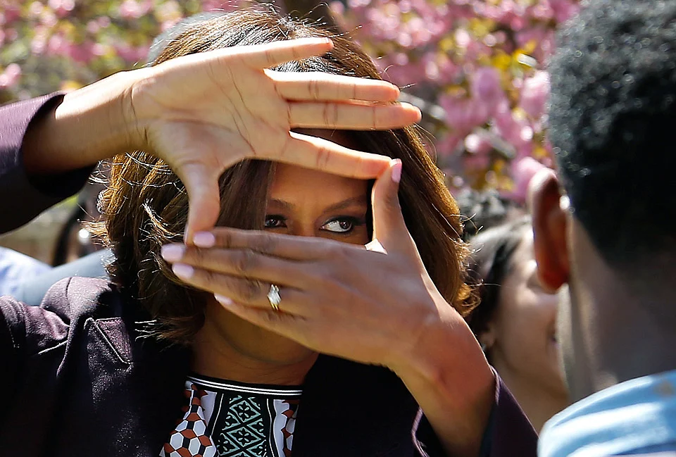 US first lady Michelle Obama obliges cheering students by showing off the hand signal the students in the quadrangle dormitory use to identify themselves