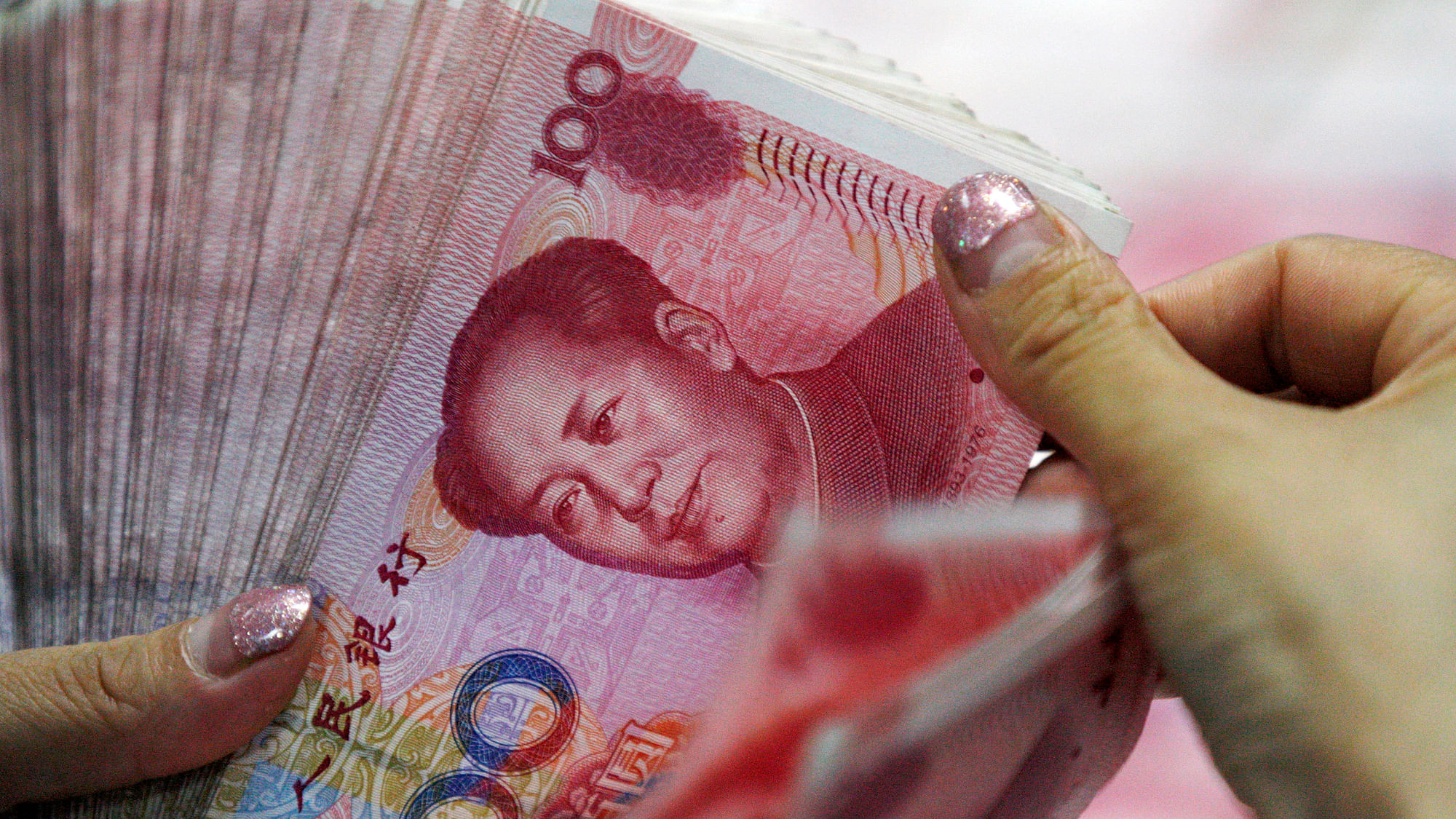 A bank clerk counts Chinese currency notes at a bank outlet in Huaibei in central China’s Anhui province. (Photo: Reuters)