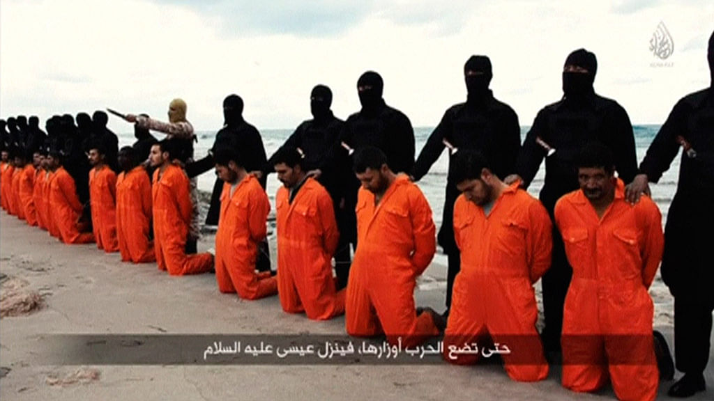 Men in orange jumpsuits held captive by the Islamic State kneel in front of armed men along a beach said to be near Tripoli on February 15, 2015. (Photo: Reuters)