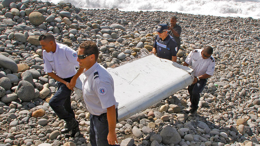 French police officers carry a piece of debris from a plane in Saint-Andre, Reunion Island. (Photo: AP)