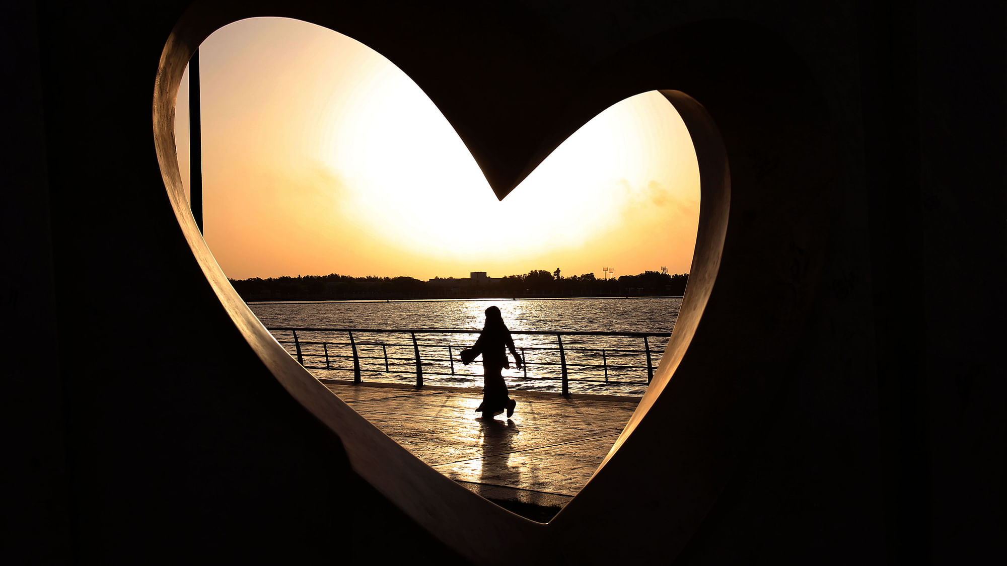 A Saudi woman walks past a heart-shaped structure. (Photo: AP)