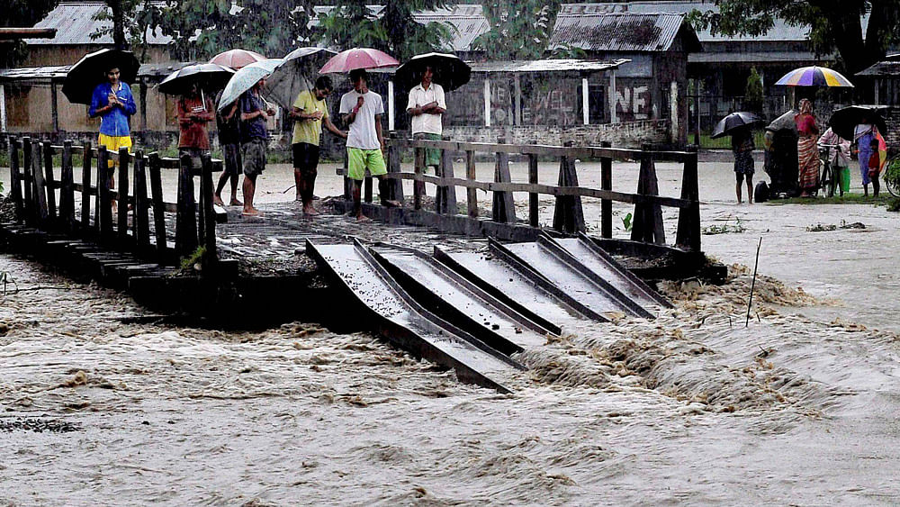 Villagers stand on a half-submerged wooden bridge in the flood hit Baska district, Assam.&nbsp;