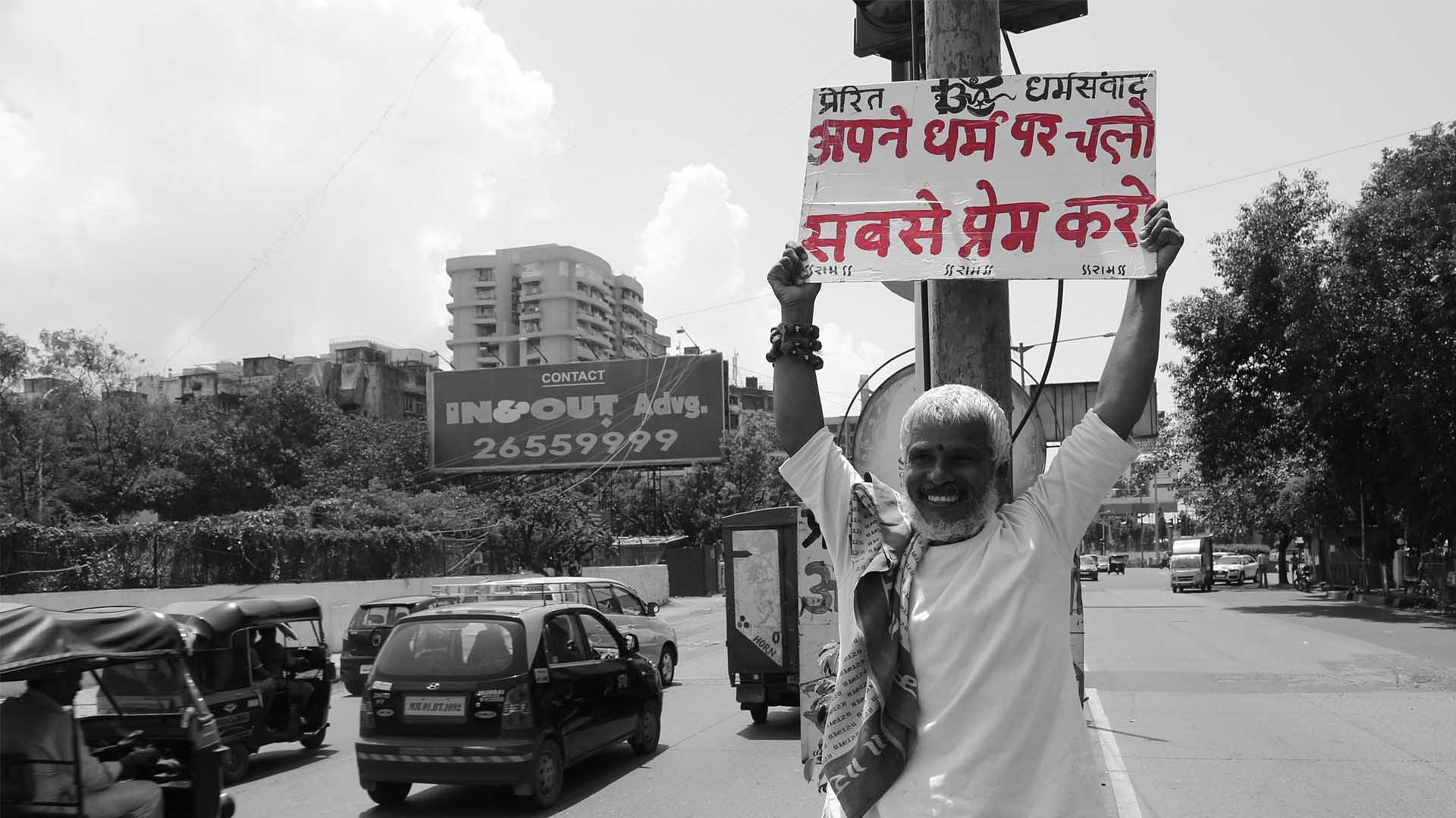 Krishnadas at Mumbai’s Juhu Circle with his placard. (Photo: <b>The Quint</b>) 