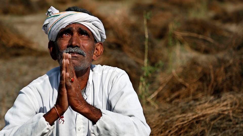 An Indian farmer looks skyward as he sits in his field with wheat crop that was damaged in unseasonal rains and hailstorm at Darbeeji village, in the western Indian state of Rajasthan.&nbsp;