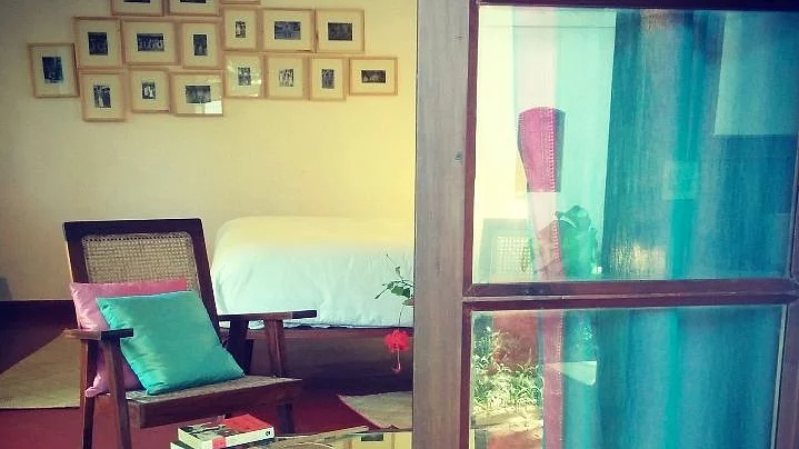 An earthy living room with a restored antique chair, colourful cushions, and frames with vintage pictures on walls (Photo: An Indian Summer)