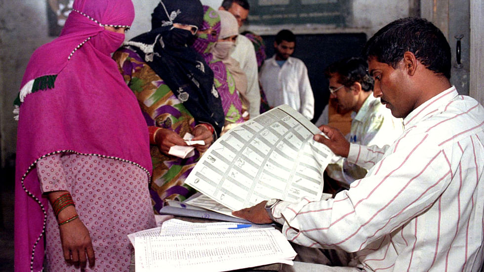 Poll official gives a ballot paper to a woman voter during the general election in Mundlana village of Haryana.