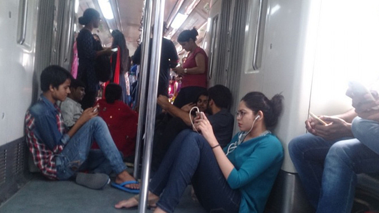 A passenger in Delhi Metro wearing earphones. (Photo: The Quint)