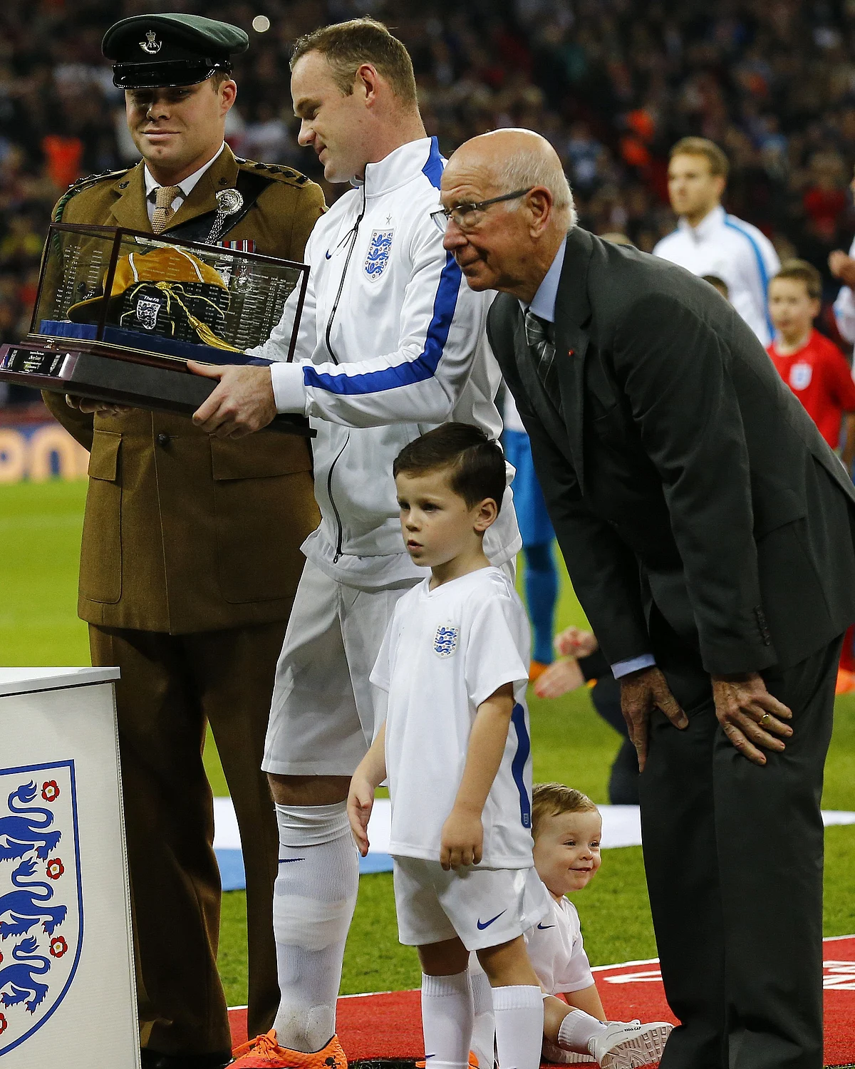Wayne Rooney receives a golden cap from Bobby Charlton marking his 100th game for England. (Photo: Reuters)