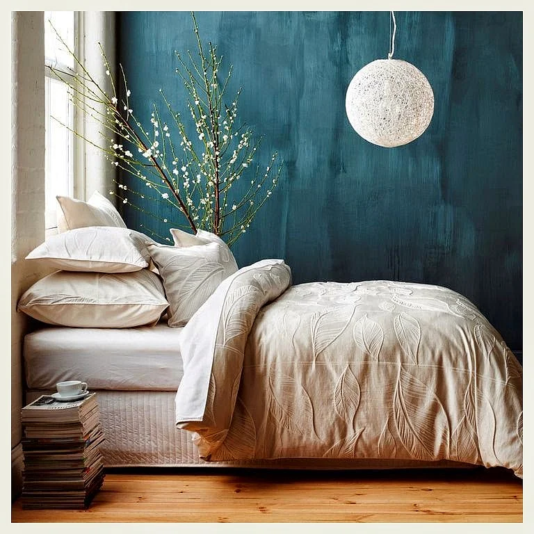 A bedroom with a table made up of a stack of magazines and an overhead lamp. (Photo: An Indian Summer)