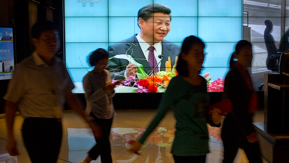 People walk past a large videoscreen showing Chinese President Xi Jinping during his trip to the United States from Chinese state broadcaster CCTV in an office building in Beijing, Friday, Sept. 25, 2015. (Photo: AP)
