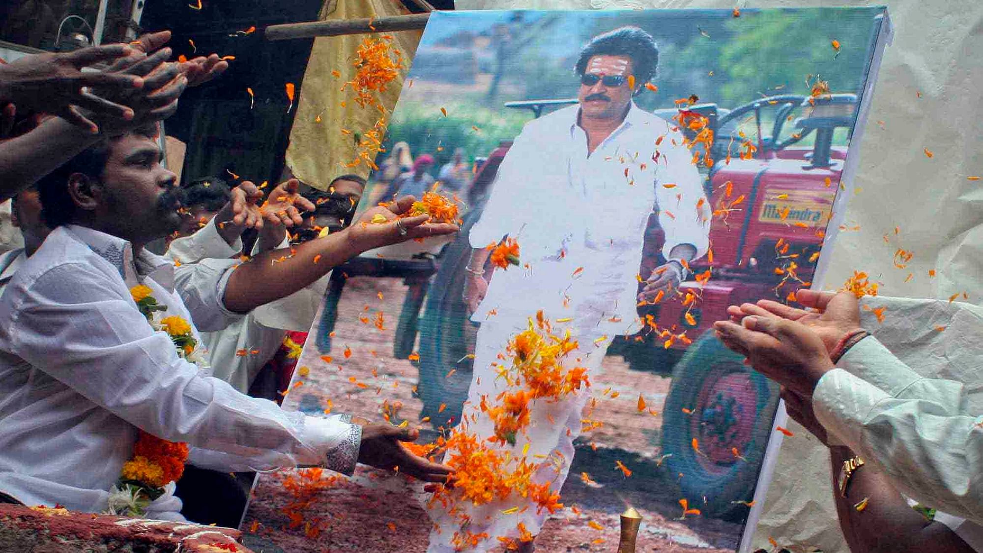 Fans of Rajinikanth throw flowers in front of his portrait (Photo: Reuters)