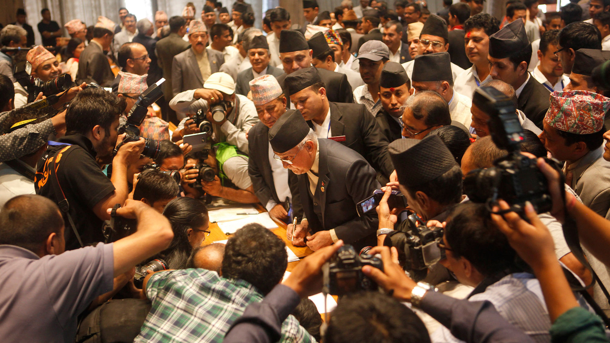  Communist Party of Nepal (Unified Marxist–Leninist) leader KP Oli (center) signs the constitution document. (Photo: AP)
